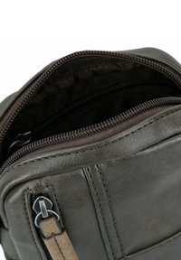 Braune Lederhandtasche mit einem Reißverschluss, der ein weiches Innenfutter zeigt, und mit detaillierten Nähten entlang der Kanten. Verfügt über einen silbernen Reißverschlussanhänger.