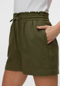 Pantalones cortos verde oliva con una cintura elástica y fruncida, y bolsillos laterales. Presentan un corte holgado y aberturas en los lados del dobladillo para mayor comodidad.