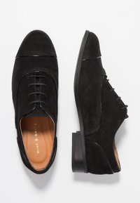 Scarpe in suede nero con punta arrotondata, design con lacci e tacco basso impilato. All'interno presentano una soletta color tan con logo dorato.