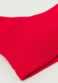 Červená texturovaná tkanina s drážkovaným vzorem, tvarovaná tak, aby na okrajích vytvářela jemné křivky. Hladký povrch s mírným leskem.