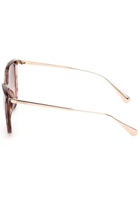 Gafas de sol marrones translúcidas con un marco rectangular, brazos de metal dorado y punteras redondeadas. Las lentes tienen un tinte en degradado.