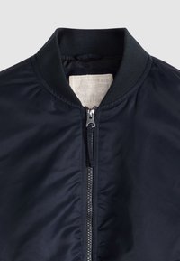 Giubbotto bomber blu navy con colletto a coste e cerniera frontale visibile, con etichetta Levi Strauss & Co. all'interno della zona del collo.