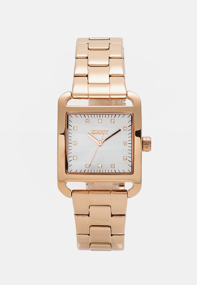 Reloj cuadrado en oro rosa con una esfera brillante de color azul claro y acentos similar a diamantes. Cuenta con una pulsera de eslabones y una corona redonda. Logo de DKNY exhibido.