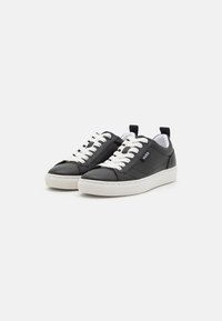 Baskets en cuir noir avec des lacets blancs et une semelle en caoutchouc blanche. Comprend un détail de logo et une languette au talon. Design classique à tige basse.