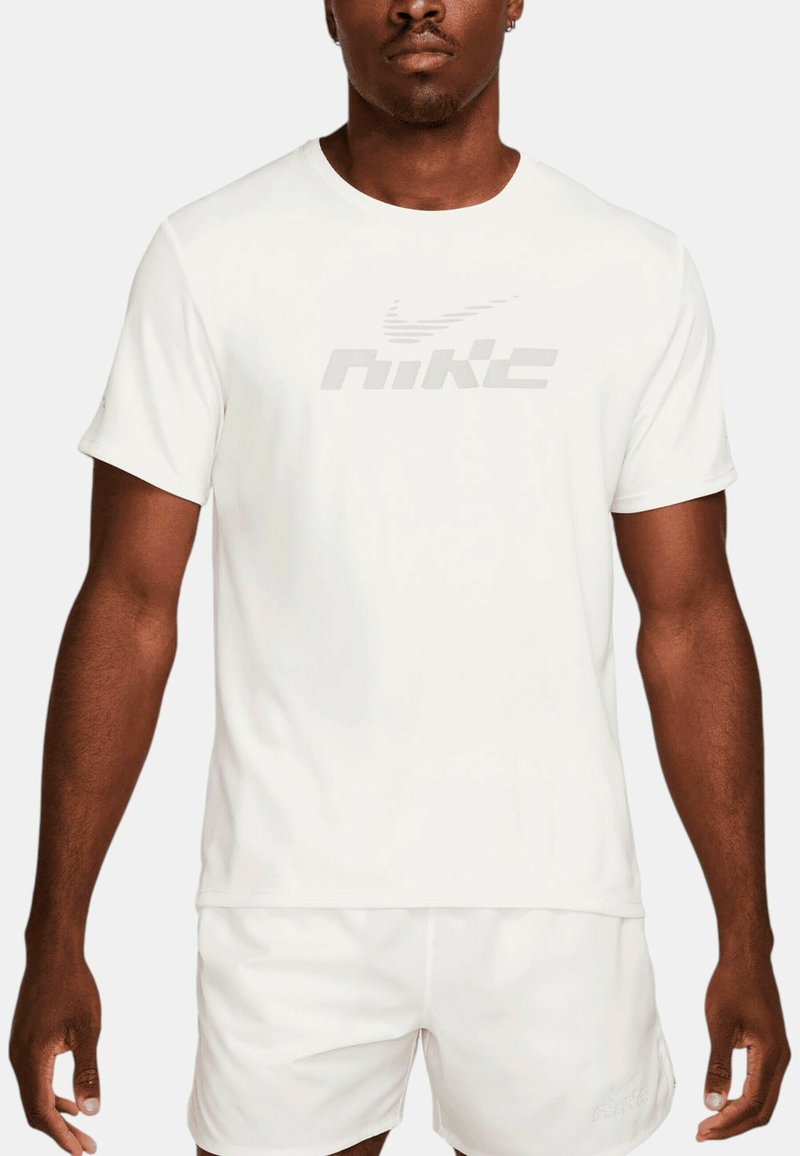Camiseta Nike blanca con cuello redondo y mangas cortas, que presenta un logotipo reflectante de Nike en el pecho. Tela ligera y suave.