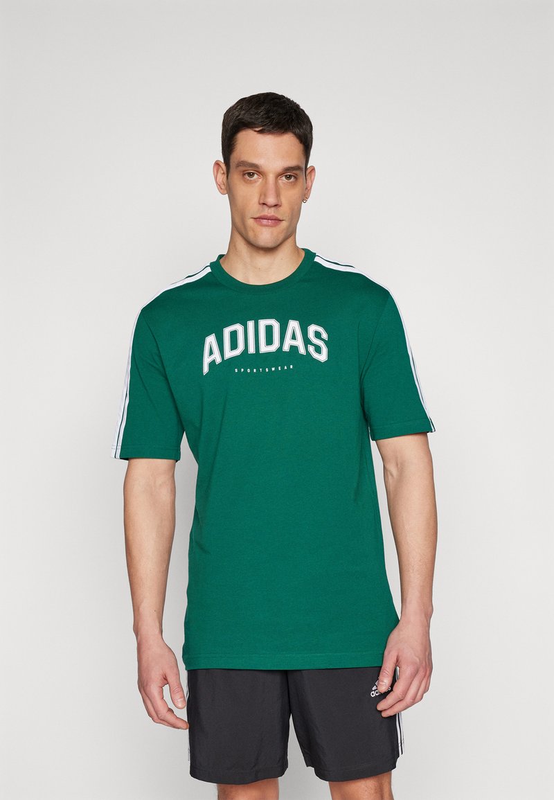 Zöld, rövid ujjú póló fehér "ADIDAS" logóval és csíkokkal a vállakon. Simább anyagból készült, kerek nyakú dizájnnal.