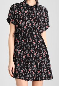 Kurzärmliges, schwarzes Kleid mit floralem Muster und Knopfverschluss. Bietet kleine rote und weiße Blumenmuster, leichtes Material und eine lockere Passform.