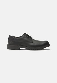 Scarpe eleganti in pelle nera con punta arrotondata, design con lacci, suola testurizzata e logo impresso sul tallone. Silhouette pulita e classica.