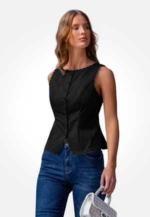 Zwarte mouwloze top met geschulpte halslijn, knopen aan de voorkant en een getailleerd silhouet, gecombineerd met blauwe jeans en een gestructureerde witte handtas.