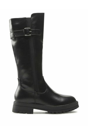 Bota de cuero negra hasta la rodilla con suela gruesa y correa decorativa con hebilla cerca de la parte superior, vista lateral sobre fondo blanco.