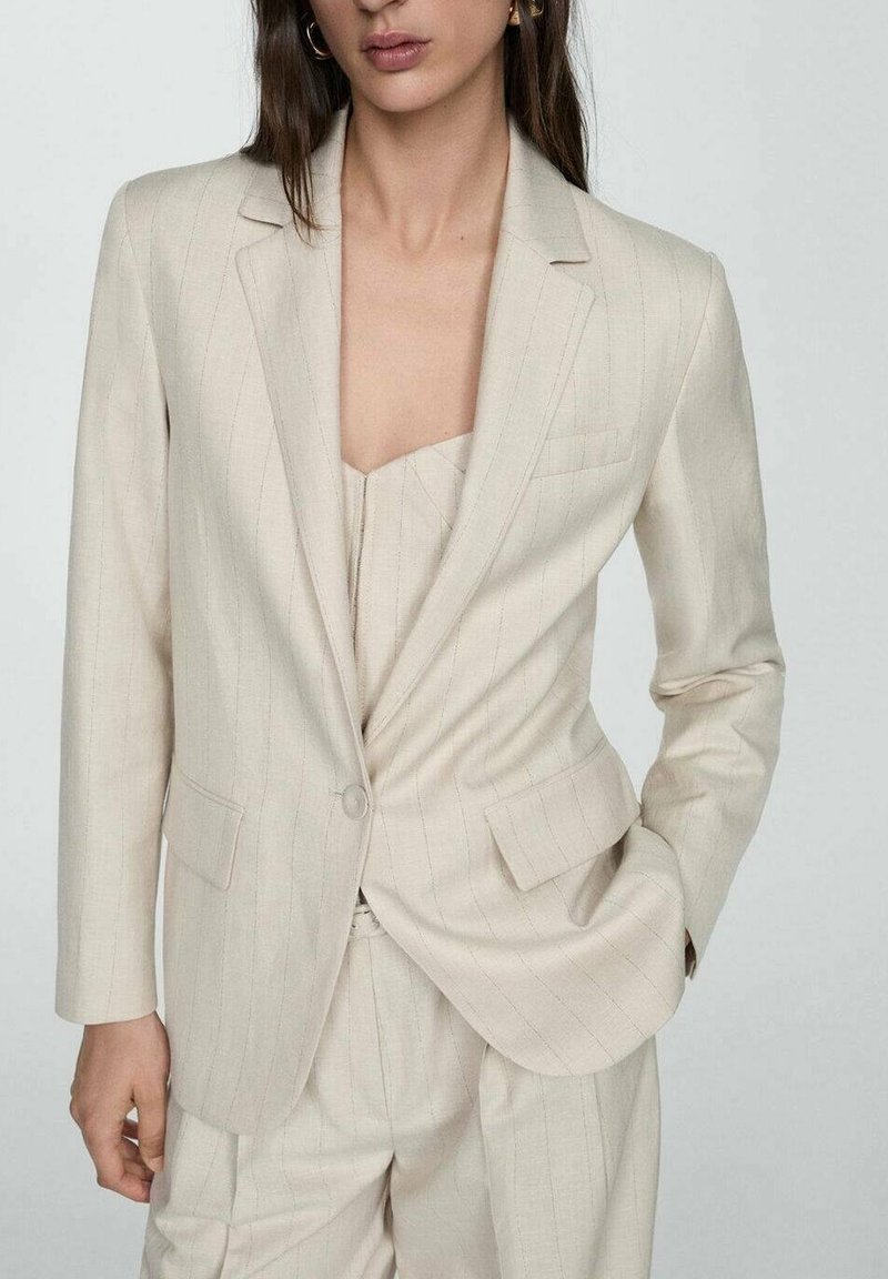 Blazer beige clair ajusté avec un bouton unique, des revers crantés et de fines rayures verticales. Confectionné dans un tissu lisse avec une légère brillance.