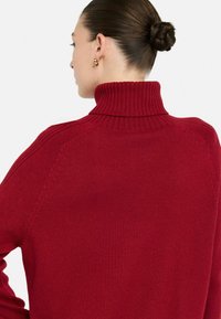 Strikket rød turtleneck sweater med ribbet tekstur, featuring dropped shoulders og sømløs skulderdetalje.