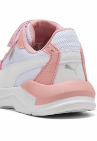 Chaussure de sport blanche avec des accents roses, dotée d'une tige en mesh, d'un col rembourré, d'une sangle à boucle et d'une semelle en caoutchouc texturée.