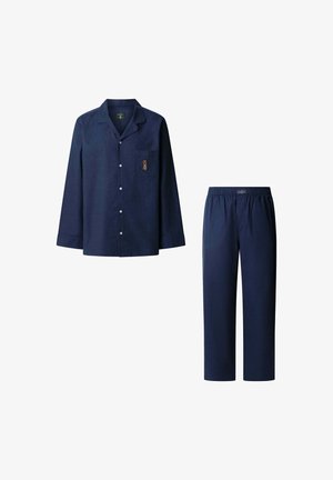 Marinblå pyjamasset i mjukt tyg. Ljusaärmad skjorta med knappar, bröstficka och broderad detalj. Avslappnade byxor med resårmidja.
