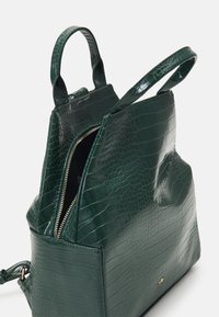 Borsa in pelle verde con stampa a coccodrillo, dotata di doppi manici superiori, chiusura a zip e forma strutturata. Accentuata da dettagli in oro.