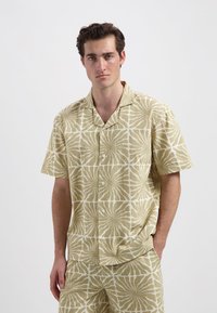 Korte mouwen overhemd met knopen in lichtgroen met een geometrisch wit patroon. Lichte stof, ontspannen pasvorm en een camp collar ontwerp.