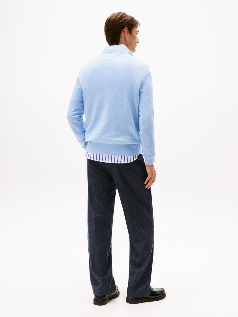 Hellblauer, strukturierten Pullover mit Kragen, kombiniert mit dunklen, weiten Hosen. Die Rückansicht zeigt ein horizontal gestreiftes Hemd darunter.