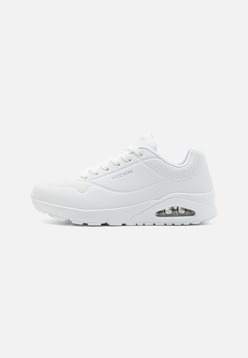Baskets de sport blanches avec des panneaux en maille, des lacets plats et une unité de coussin d'air visible dans la semelle. Présente un design lisse et arrondi.