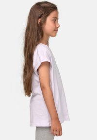T-shirt viola a maniche corte con maniche arrotolate, dal tessuto morbido e una vestibilità comoda, abbinato a leggings grigi. Mostra una vista laterale.