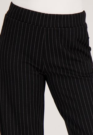 Zwarte broek met verticale strepen en een aangesloten tailleband, gemaakt van gladde stof, met subtiele metalen accenten in de strepen.