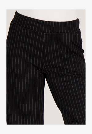 Zwarte broek met verticale strepen en een aangesloten tailleband, gemaakt van gladde stof, met subtiele metalen accenten in de strepen.