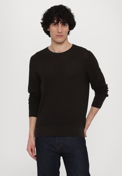Dunkelbrauner, strukturierter Strickpullover mit langen Ärmeln und Rundhalsausschnitt, kombiniert mit dunklen Jeans. Einfaches Design, keine sichtbaren Muster.