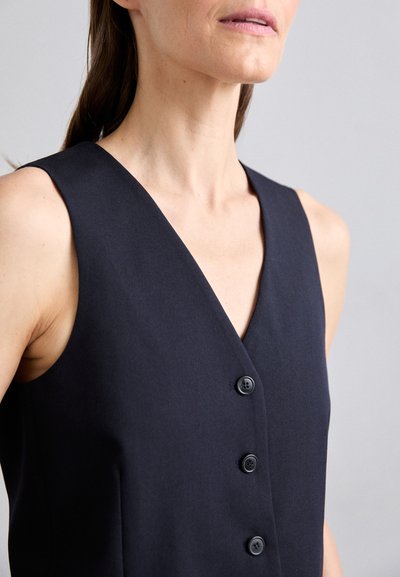 Black sleeveless dress with a V-neckline, featuring three front buttons and seamless shoulders. Made of a smooth, lightweight fabric.