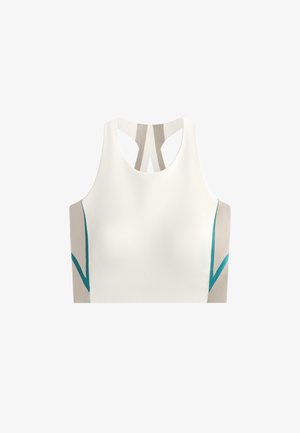 Fehér sportos crop top racerback fazonnal. Bézs és türkiz színű részletekkel az oldalán és hátulján, amelyek színblokkolt hatást biztosítanak.