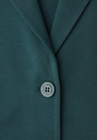 Veste vert foncé avec col à revers cranté et un bouton à quatre trous gravé "StreetOne" fermant le devant.
