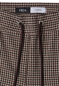 Pants waistband with black and white houndstooth pattern, dark brown drawstring, and label reading "CECIL PANTS".