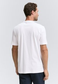 Hvid bomulds t-shirt med korte ærmer, rund halsudskæring og et enkelt design. Synlig syning langs kanten og ærmerne.