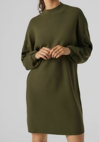 Pletené, dlouhé, oversized šaty v tmavě zelené barvě, s vysokým výstřihem a žebrovanými manžetami. Měkká textura a jednoduchý design.