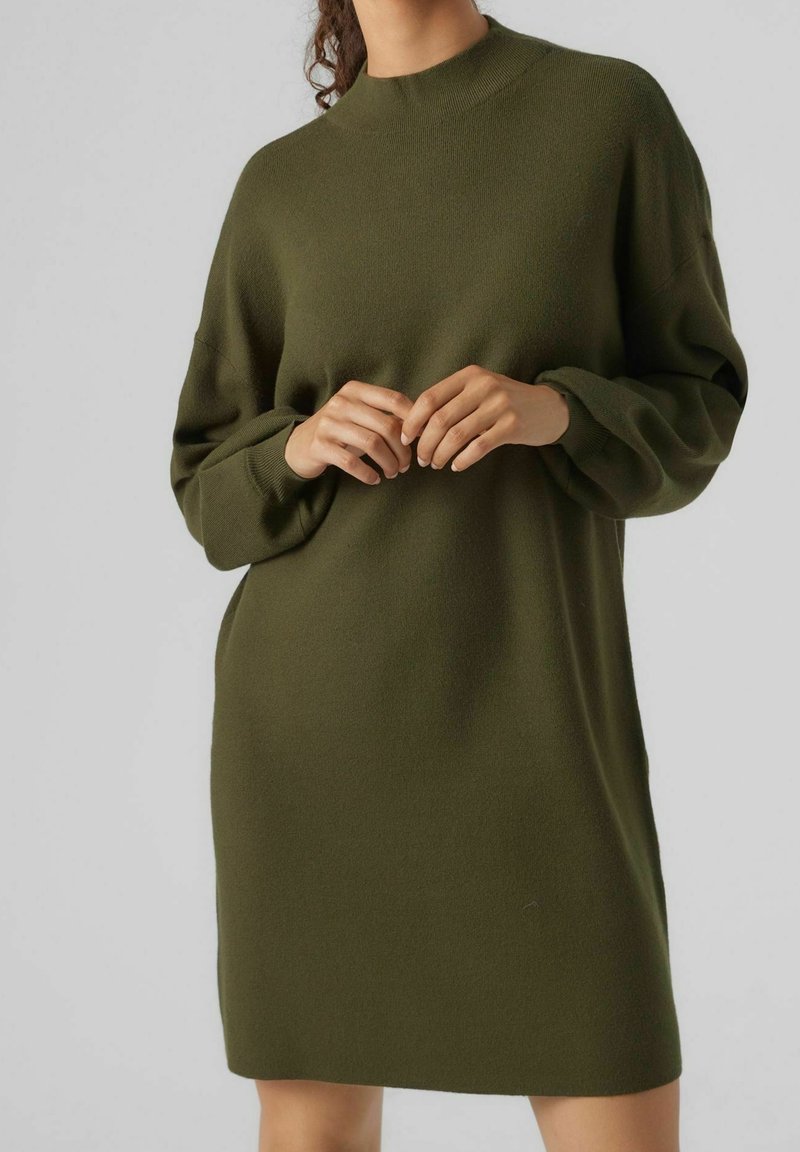 Pletené, dlouhé, oversized šaty v tmavě zelené barvě, s vysokým výstřihem a žebrovanými manžetami. Měkká textura a jednoduchý design.