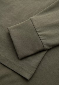 Olivengrünes Baumwollhemd mit langen Ärmeln, Rundhalsausschnitt und umgeschlagenen Ärmeln. Weiche Textur und flache Nähte.