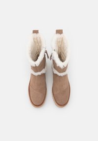 Botine din suede maro, cu căptușeală din blană sintetică albă, vârf rotunjit, cusături contrastante și banda de prindere pe laterale pentru a fi încălțate cu ușurință.