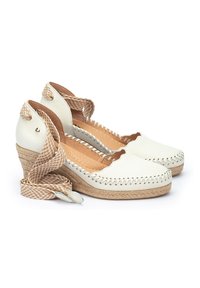 Chaussures compensées blanches en cuir avec des accents tressés en tan, un design festonné et une lanière tressée. La semelle en liège apporte texture et hauteur.