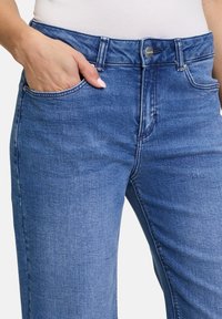 Blaue Jeans aus Denim mit mittelhohem Bund, fünf Taschen und leichter Ausbleichung für einen klassischen Look. Weiche Textur mit sichtbaren Nähten.