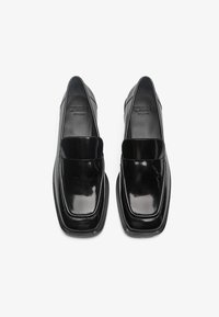 Women's black patent leather loafers with a glossy finish, square toe, flat sole, and minimalistic design.