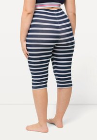 Námořnické modré a bílé pruhované capri legíny s přiléhavým střihem, elastickým pasem a kotníkovou délkou, vyrobené ze pružného materiálu.