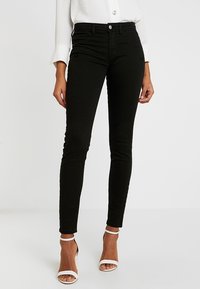 Svarta jeans i stretchbomull, slim fit, med medelhög midja, med knappstängning, fem fickor och en slät textur.