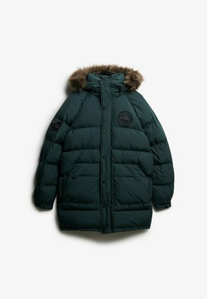 Mørkegrønne pufferjakke med hætte med pelskant. Har et rundt logo-patch på brystet og trykknaplukninger. Blødt materiale og isoleret design.