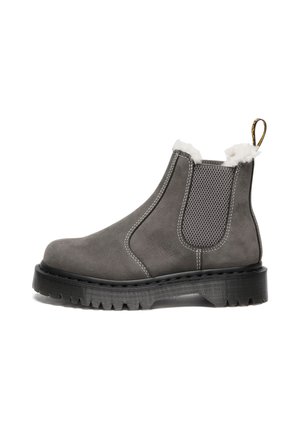 Stivaletto in camoscio grigio con suola in gomma, pannelli elastici ai lati e bordo in pelliccia sintetica bianca. Presenta cuciture a contrasto e un linguetta per il pull.