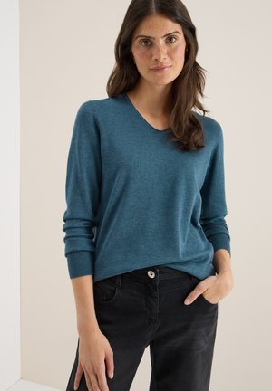 Teal v-hals trui van zachte gebreide stof, voorzien van lange mouwen en ribbels bij de manchetten, gecombineerd met zwarte broek en knoopdetails.