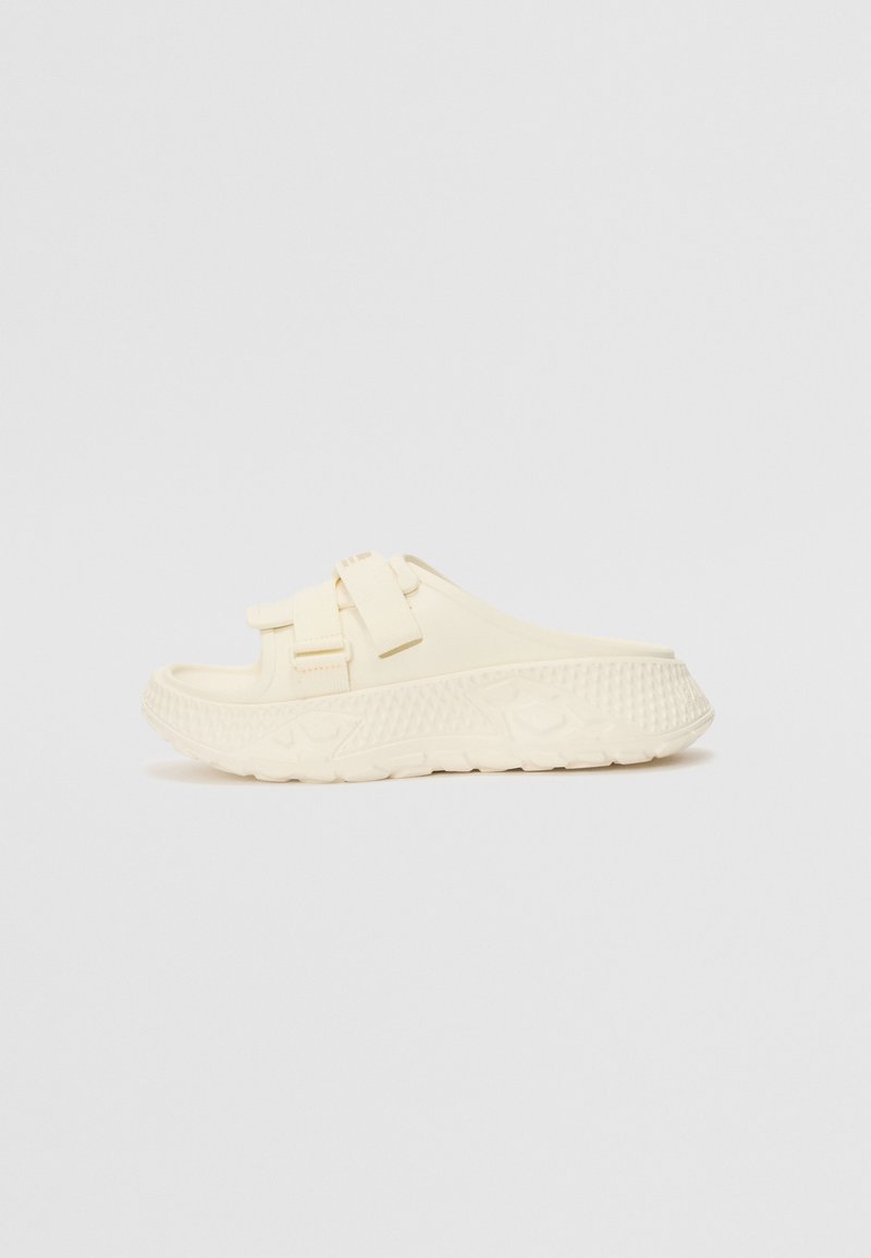 Kremkrāsas slaida sandaļi, izgatavoti no gumijas. Aprīkoti ar diviem regulējamiem siksnām un strukturētu zoli ar ģeometrisku rakstu, kas nodrošina saķeri.