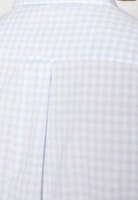 Světle modrá a bílá kostkovaná košile s zadním skladem a hladkou texturou látky, s klasickým límcem.