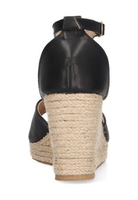 Sandalia de cuña de cuero negro con tacón de yute trenzado, tira de tobillo y diseño de punta abierta. Textura y detalles de costura visibles en el tacón.