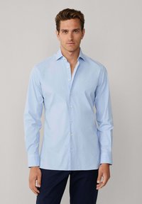 Lichtblauw overhemd met lange mouwen, een klassieke kraag en een klein logodetail op de borst. Gemaakt van gladde, lichtgewicht stof.