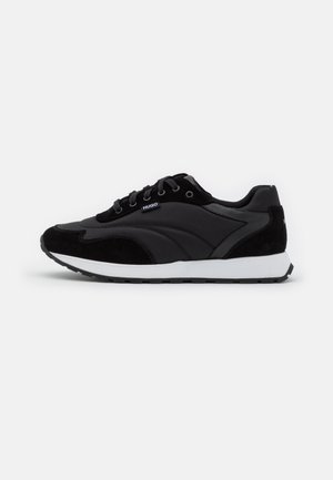 Czarny niskoprofilowy sneaker z białą podeszwą, sznurowaniem z przodu, panelami z zamszu i tkaniny oraz małym logo "HUGO" po boku.