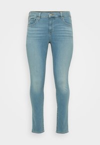 Jeans de denim azul claro con un corte ajustado, cintura de altura media, diseño de cinco bolsillos y un ligero desvanecimiento. La tela tiene una textura suave.