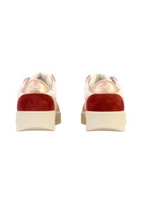 Sneaker rosse e bianche con accentuazioni in suede, materiali testurizzati, suola piatta e dettaglio di branding metallico sul tallone.